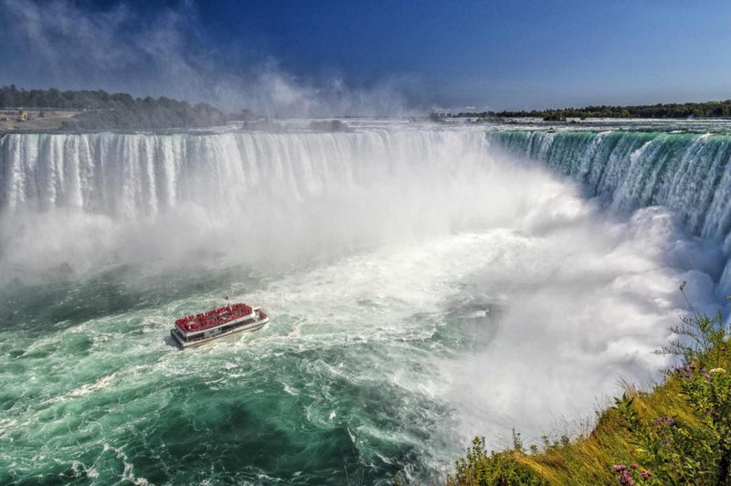A Niagara City Cruises boat crowded with red ponchos in the Horseshoe Falls basin