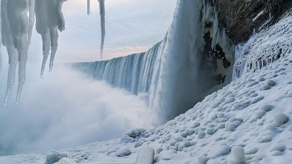 Icicles hanging above the brink of the Horseshoe Falls with the frozen ice field below