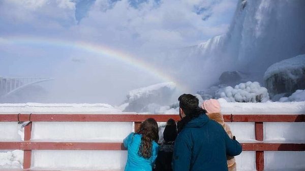 A rainbow forming in the spray over the frozen falls