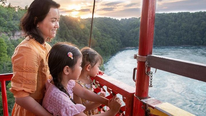 A family looking out from the Whirlpool Aero Car over the Niagara River gorge at sunset